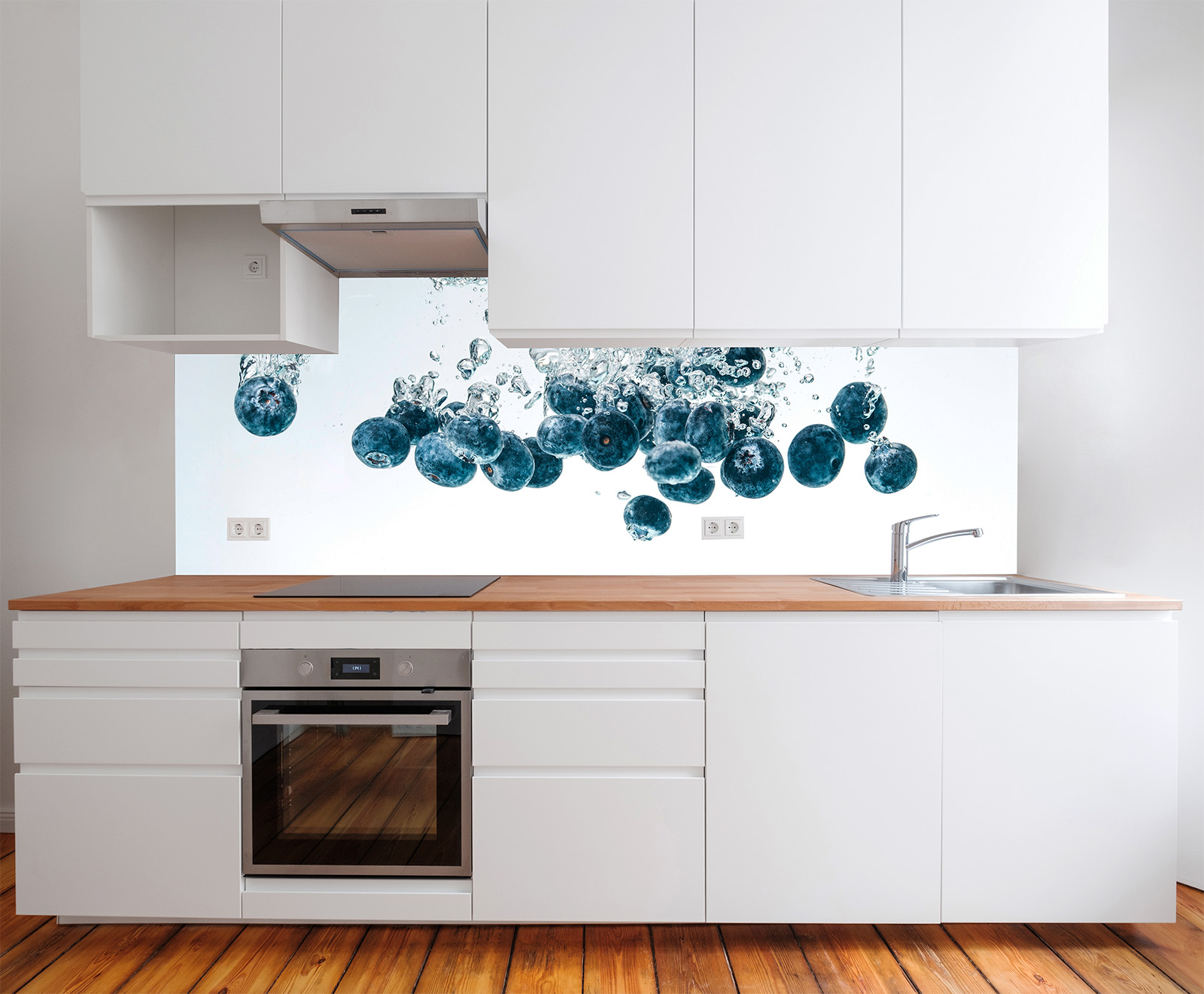 Küche mit weißen Schränken und Holzarbeitsplatte, im Hintergrund spritzende Blaubeeren in Wasser.