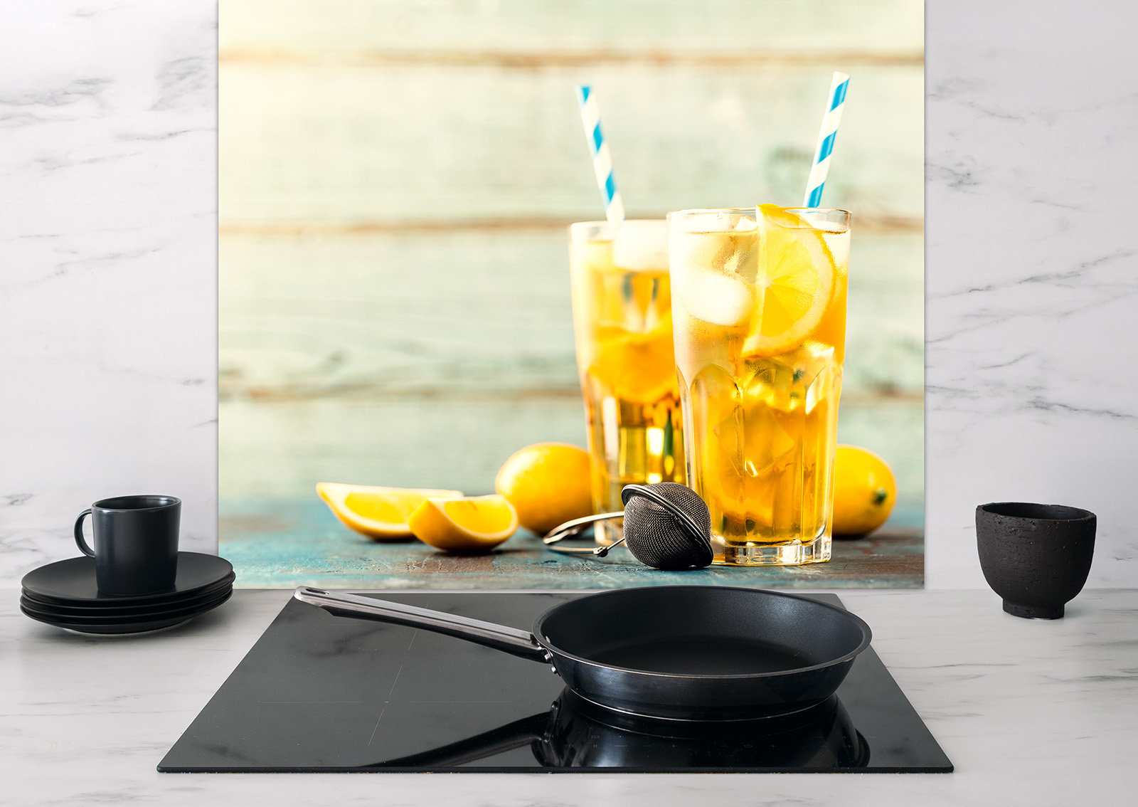 Spritzschutz Orangenlimonade mit zwei Gläsern Limonade, Zitronenscheiben und einer Zitrone auf einem Tisch.