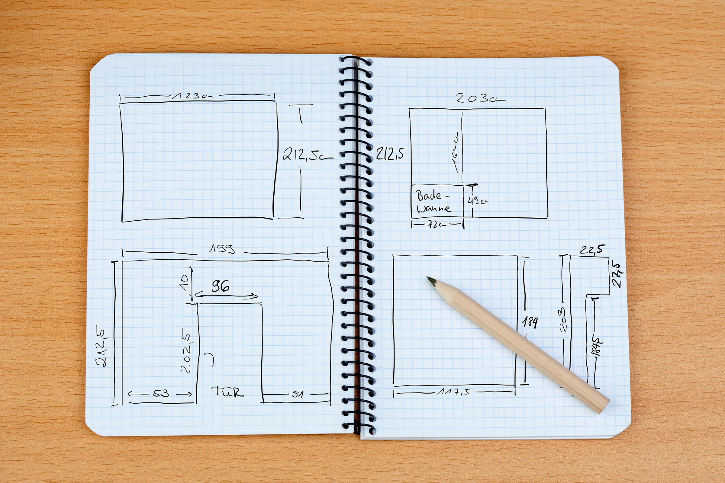 Technische Skizze in einem Notizbuch mit Maßen für ein Projekt, Bleistift daneben.
