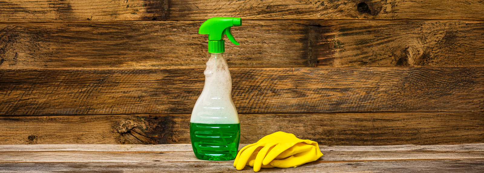 Reinigungsmittel Breit in einer Sprühflasche mit grünem Sprühkopf, daneben gelbe Gummihandschuhe.