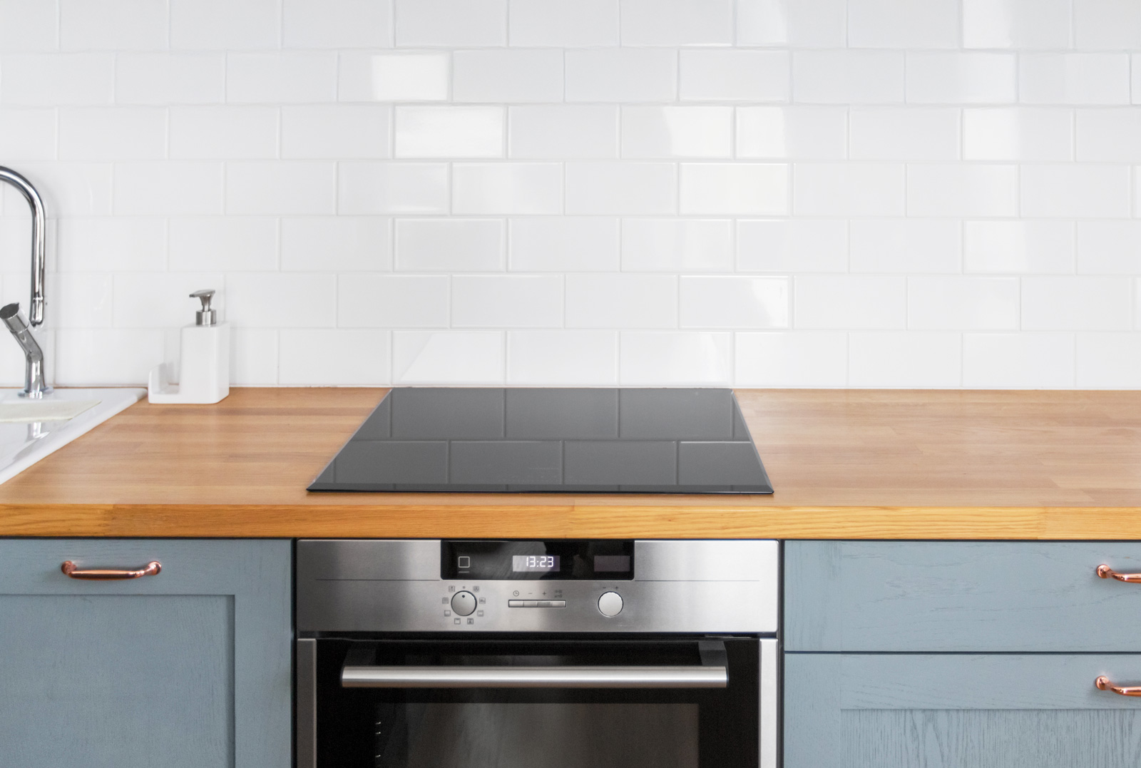 Küchenarbeitsplatte mit Kochfeld und Spüle, im Hintergrund weiße Fliesen.